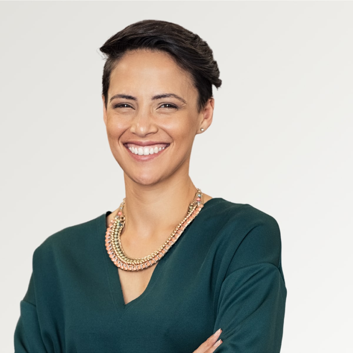 Una mujer con el pelo corto y un collar está sonriendo.